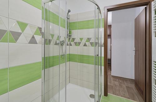a bathroom with a shower with green and white tiles at Restaurant Penzion City in Jirkov