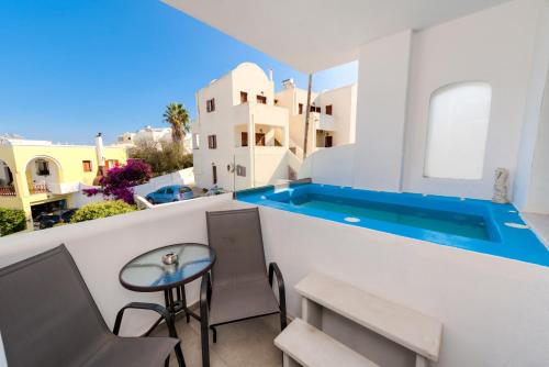 a balcony with a table and a swimming pool at The Muses of Santorini Private Jacuzzi Suites in Vóthon