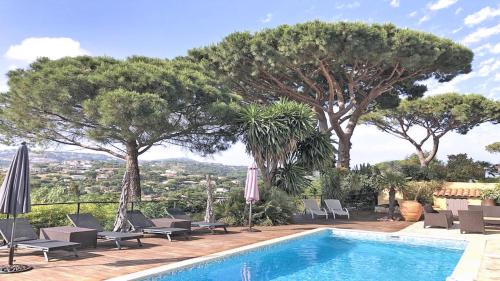 - une piscine avec des chaises, des parasols et des arbres dans l'établissement Les Geais - Marevalande, à Sainte-Maxime