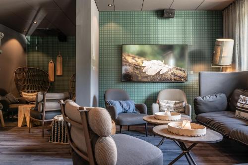 a waiting room with couches chairs and tables at Hotell Storforsen in Bredsel