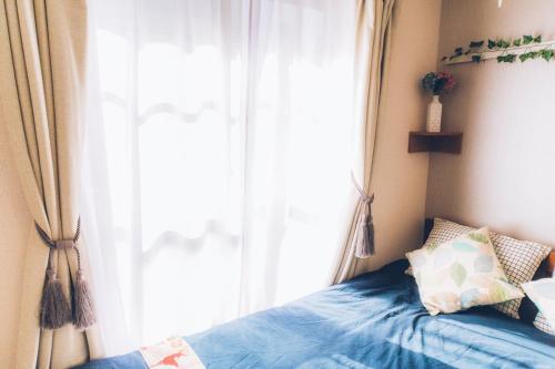 a bedroom with a blue bed with a window at nestay suite tokyo shibuya in Tokyo