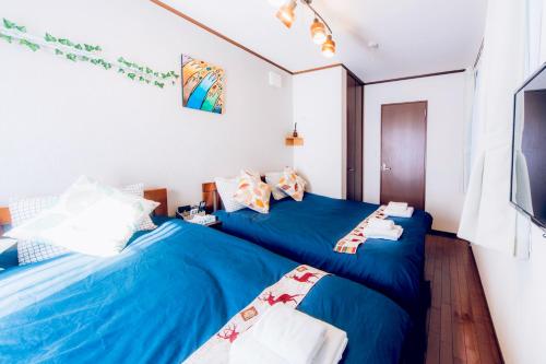 two beds in a room with blue sheets at nestay suite tokyo shibuya in Tokyo