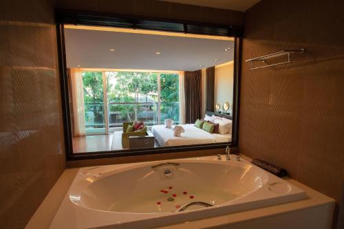 卡隆沙灘的住宿－Peach Blossom Resort & Pool Villa - SHA Plus，一个带大镜子的房间内的大浴缸