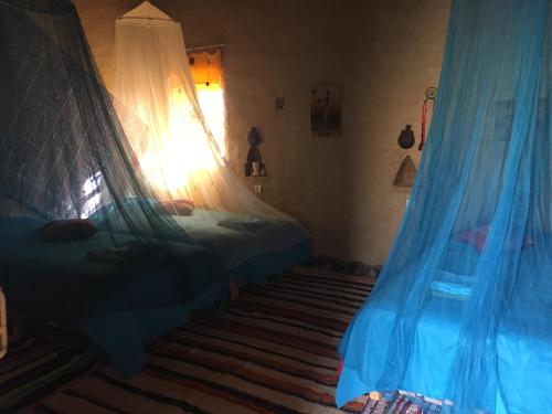 a bedroom with two beds with blue drapes at Kasbah Luna del Sur in Merzane