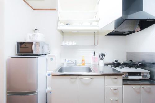 a kitchen with a sink and a refrigerator at nestay suite tokyo shibuya in Tokyo