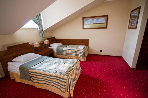 a hotel room with two beds and a red carpet at Browar Sulewski in Hrubieszów
