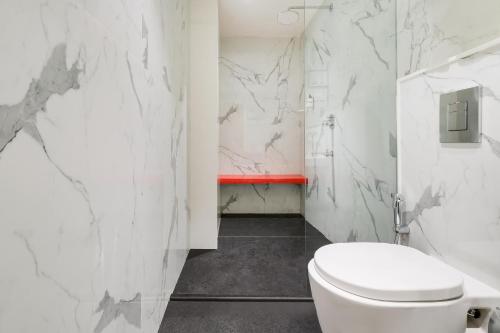 a white bathroom with a toilet and a red bench at Red Fox Hotel, Vijayawada in Vijayawāda