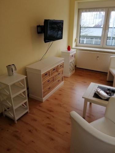 a living room with white furniture and a flat screen tv at Gästehaus Schiemann in Teterow