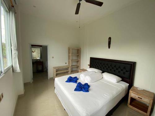 ein Schlafzimmer mit einem Bett mit blauen Bogen darauf in der Unterkunft Vila Troja Kubu in Tulamben