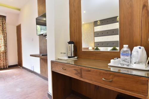 a kitchen with a wooden dresser with a mirror at Hotel Snowcrests Manor in Manāli