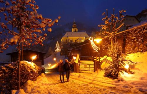 two people walking down a snow covered street at night at Appartements Stockinger in Grossarl