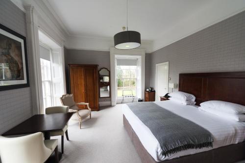 um quarto com uma cama grande, uma secretária e cadeiras em Belmont House Hotel em Banbridge