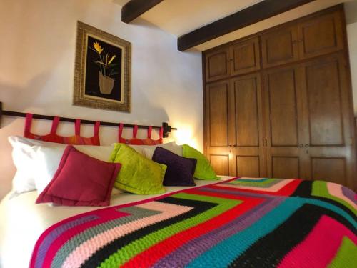 ein Schlafzimmer mit einem Bett mit bunten Kissen darauf in der Unterkunft Pousada Villa D'Amore in Monte Verde
