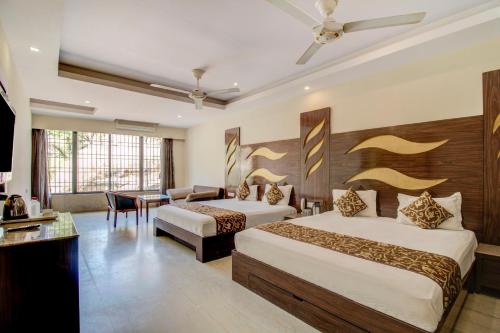 a hotel room with two beds and a desk at Hotel Royale Palace in Mount Ābu