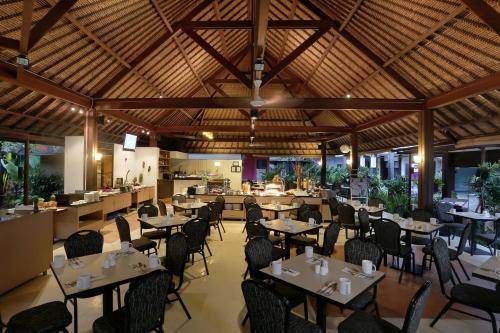 a restaurant with tables and chairs in a room at Kuta Central Park Hotel in Kuta