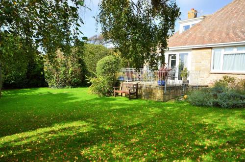 a yard with a bench and a house at Whitestones in Brighstone
