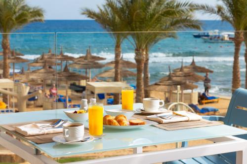 a table with a plate of food and a view of the beach at Beach Albatros Aqua Park - Hurghada in Hurghada