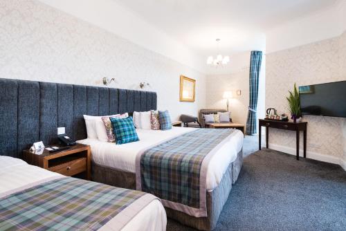 a hotel room with two beds and a tv at The Atholl Palace in Pitlochry
