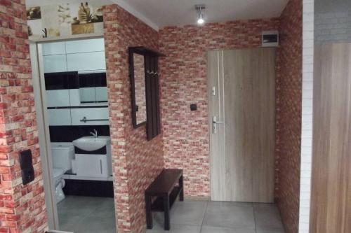 uma casa de banho com uma parede de tijolos, uma porta e um lavatório. em Nad Kamienną em Jelenia Góra