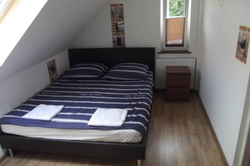 a bed with blue and white striped sheets in a room at Nad Kamienną in Jelenia Góra