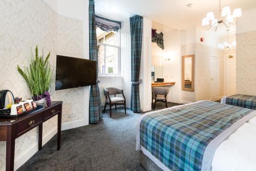 a hotel room with a bed and a flat screen tv at The Atholl Palace in Pitlochry