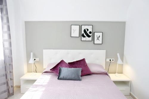 デニアにあるApartamento Maravista - Deniasolの白いベッドルーム(紫色の枕を使用した大型ベッド1台付)