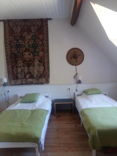 Cette chambre comprend 2 lits et un tapis sur le mur. dans l'établissement Maintenon Saint Martin de nigelles, maison d'hôtes Marguerite, à Églancourt