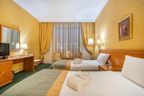 カザンにあるSuleiman Palace Hotelのベッド2台とデスクが備わるホテルルームです。