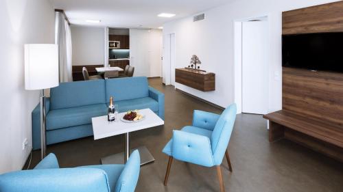 sala de estar con muebles azules, mesa y sillas en Apart-Hotel FirstBoarding Bayreuth, en Bayreuth