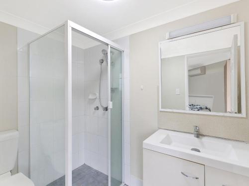 a white bathroom with a shower and a sink at Mariners Apartment 21 in The Entrance