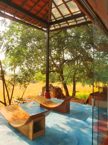 a pavilion with two wooden benches and a tree at Seclude Falling Cashews, Chorao Island, North Goa in Chorao