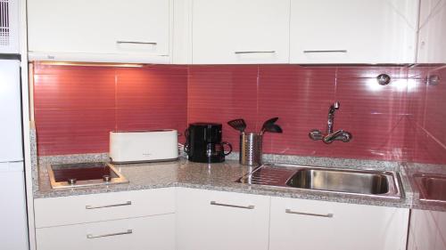 a kitchen with white cabinets and a sink and red tiles at Marlenghi Apartments View Canteras in Las Palmas de Gran Canaria