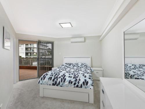 a bedroom with a bed with a black and white comforter at Mariners Apartment 21 in The Entrance
