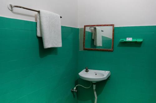 a green bathroom with a sink and a mirror at Hotel AKMG in Dindigul