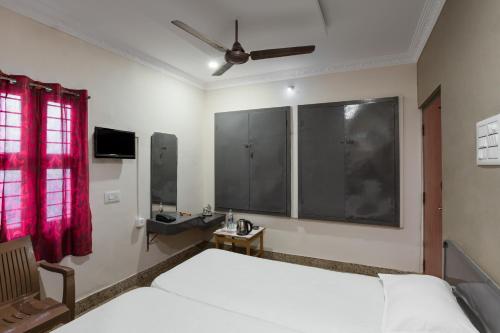 a bedroom with a white bed and a red window at Hotel AKMG in Dindigul
