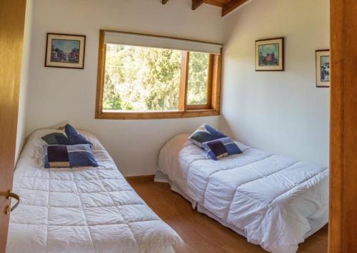 1 dormitorio con 2 camas y ventana en Casa Roma en Villa La Angostura