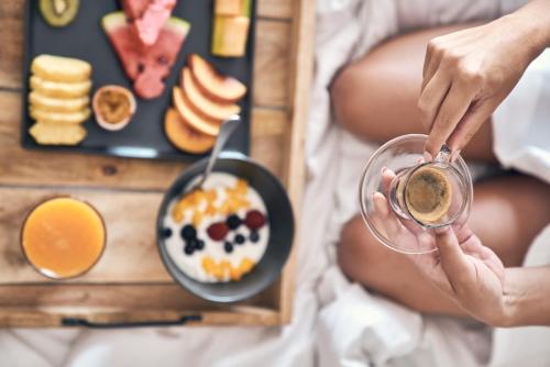 Een persoon met een glas koffie en een bord met ontbijt. bij Mykonos Bliss - Cozy Suites, Adults Only Hotel in Kalo Livadi