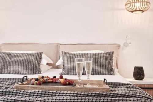 een dienblad met twee champagneglazen en fruit op een bed bij Mykonos Bliss - Cozy Suites, Adults Only Hotel in Kalo Livadi