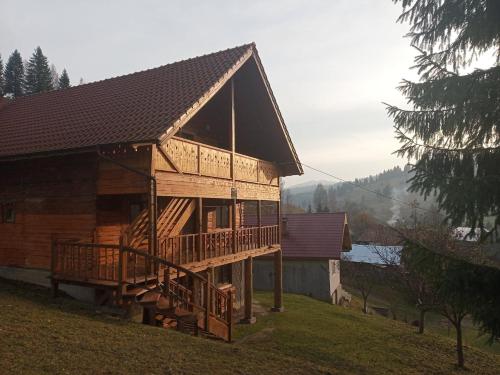 una gran casa de madera con terraza en una colina en Flower Bell, en Ghimeş-Făget