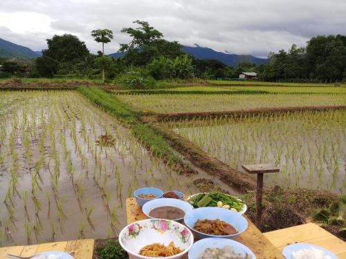 a table with food on it next to a rice field at Chill House Mae Sariang in Ban Mae Salap