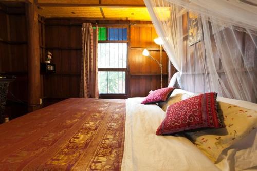 1 dormitorio con cama con almohadas y ventana en Chiang Mai Summer Resort en Chiang Mai
