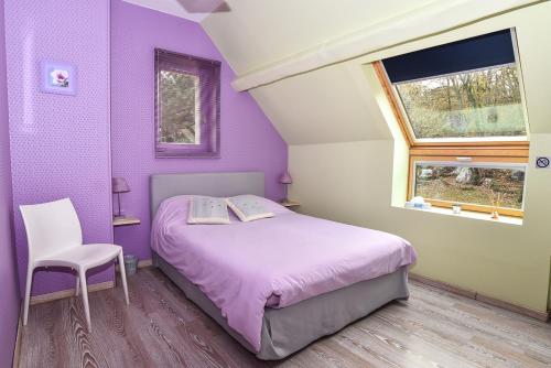 Dormitorio púrpura con cama y silla en Le Jardin des Roches, en Moigny