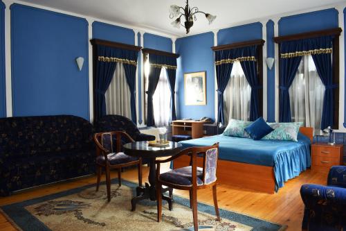 um quarto azul com uma cama, uma mesa e cadeiras em Belle Ville Hotel em Plovdiv