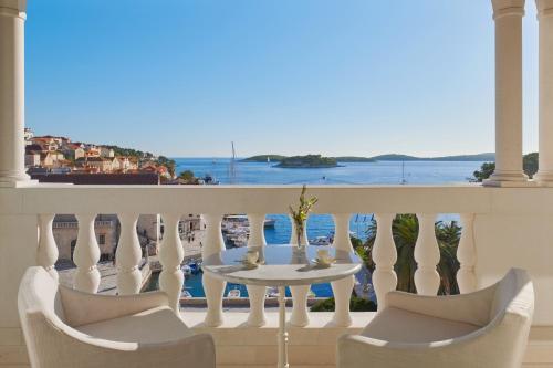 a balcony with a table and chairs and a view of the water at Palace Elisabeth Hvar Hotel - The Leading Hotels of the World in Hvar
