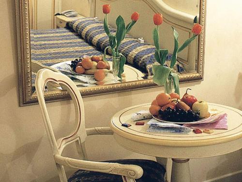 a mirror and a plate of fruit on a chair in a room at Vip's Motel Luxury Accommodation & Spa in Lonato del Garda