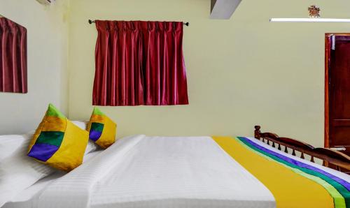 a bedroom with a large white bed with colorful pillows at Umaiyyal Home Stay in Kanyakumari