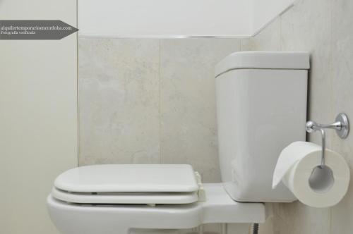 a white toilet in a bathroom with a roll of toilet paper at Departamentos Lugar in Cordoba