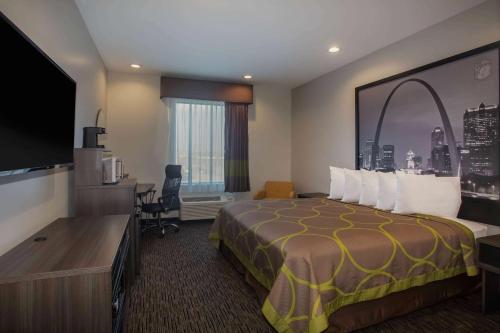 a hotel room with a bed and a flat screen tv at Super 8 by Wyndham St. Louis North in Saint Louis