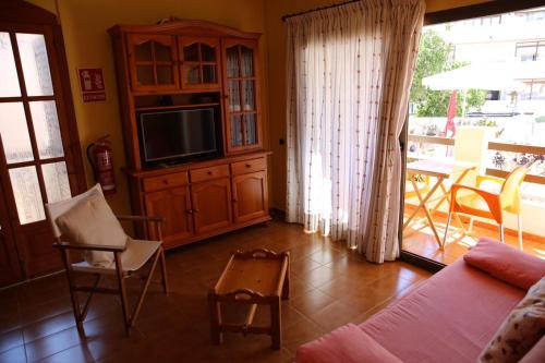 un soggiorno con divano, TV e tavolo di Isla Blanca II 3 ET 249 PL a Es Pujols