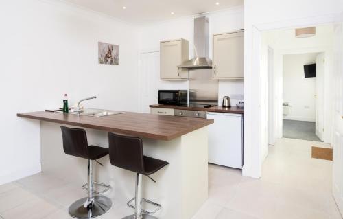 a white kitchen with a wooden counter and stools at The Atholl Palace in Pitlochry